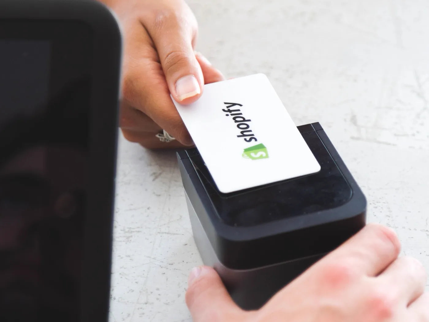 A Shopify card being inserted into a card reader at a counter, next to a tablet